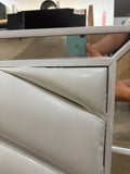Close-up of the footboard corner showing the mirrored trim and the upholstery pulling away slightly (open box)