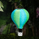 Alpine solar hot air balloon lantern – green/blue hanging in a garden