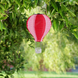 Alpine solar hot air balloon lantern – red/pink hanging in a tree
