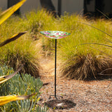 Alpine 10 inch glass stake birdbath with flowers and hummingbird – in a garden bed