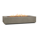 Real Flame Aegean 70 inch rectangle propane fire pit table in Mist Gray – lit, with lava rock (stock photo)