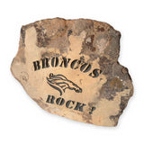 Hand-engraved natural sandstone garden stone reading "BRONCOS ROCK!" with a horse-head design – front on white