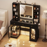 Black vanity desk with lighted mirror and glass cabinets in a bedroom – angled view (manufacturer image)